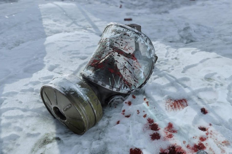 A bloodied and broken gas mask lying in blood-stained snow
